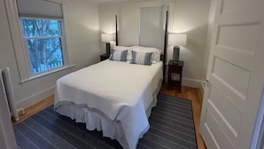 A bedroom with a bed, two bedside tables, a window, and a door. - Waterfront 2 Bedroom Unit (Salem)