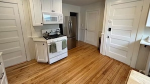 A kitchen with white cabinets, a stove, a microwave, and a refrigerator. - Waterfront 2 Bedroom Unit (Salem)