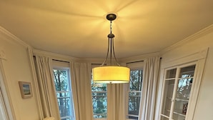A dining room with a round table, four chairs, a hanging lamp, and a patterned rug. - Waterfront 2 Bedroom Unit (Salem)