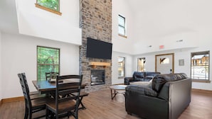 A spacious living area with a stone fireplace, a leather sofa, and a dining table with chairs.
