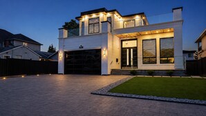 Une maison moderne à deux étages, dotée d’un garage, d’une allée bien éclairée et d’une petite pelouse.