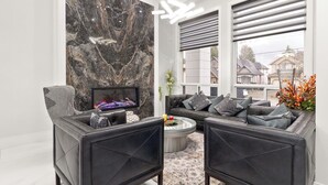 Un salon moderne avec un mur d’accent en marbre, des canapés en cuir, une table basse en verre et un téléviseur.