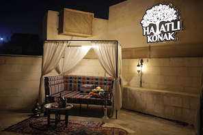A traditional room with a sofa, a table with a bottle, and a decorative lamp. - HAYATLI KONAK (Şanlıurfa)