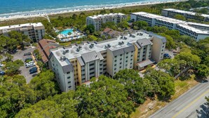 Un hôtel à plusieurs étages doté d’une piscine, situé près d’une plage et offrant une vue dégagée sur l’océan.