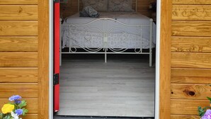 Una cabaña de madera con una cama, un cuadro en la pared y un ventanal pequeño.