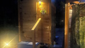 Una cabaña de madera con un pequeño porche y una planta colgante.