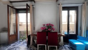 A room with a marble floor, a wooden table with two chairs, a vase of flowers, and a blue sofa. - Cozy Sweet Marbel room in the center of Florence (Firenze)