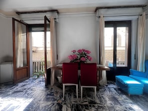 A room with a marble floor, a wooden table with two chairs, a vase of flowers, and a blue sofa. - Cozy Sweet Marbel room in the center of Florence (Firenze)