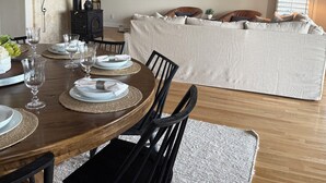 Comedor con una mesa redonda de madera dispuesta para seis personas, sillas negras y una estufa negra al fondo.