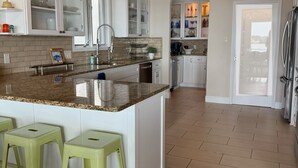 Una cocina amplia con una isla grande, armarios blancos y piso de madera.