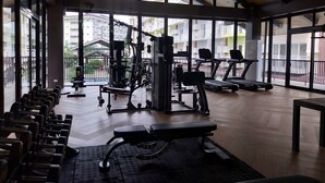 Une salle de sport équipée de machines d’exercice, de bancs et de tapis de course.