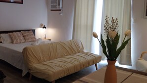 Une chambre à coucher comprenant un lit, un canapé, une table à manger avec un vase et un ventilateur de plafond.