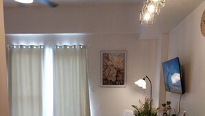 Un salon moderne avec un canapé, une table basse, un téléviseur et un ventilateur de plafond.