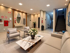 Un moderno vestíbulo de hotel con una mesa de centro de mármol, una zona de estar y una escalera.