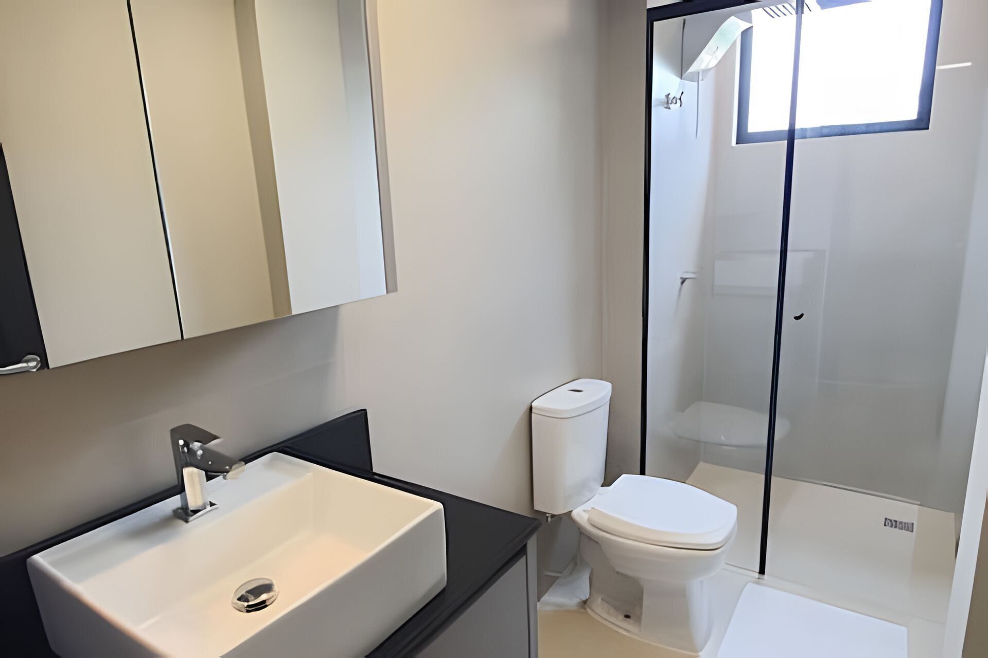 Une salle de bain moderne avec un lavabo blanc, des toilettes et une douche à parois de verre.