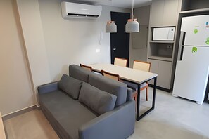 A modern kitchen with a dining area, including a sofa and chairs. - Residencial HS (Foz do Iguacu)