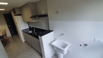 Eine moderne Küche mit schwarzer Arbeitsplatte, weißen Schränken, einem eingebauten Kochfeld und einem weißen Spülbecken.