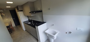 A modern kitchen with a black countertop, white cabinets, a built-in stove, and a white sink. - Residencial HS (Foz do Iguacu)
