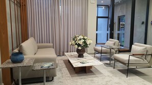 Una hall d'hotel moderna con un divano, poltrone, un tavolino e un vaso di fiori.