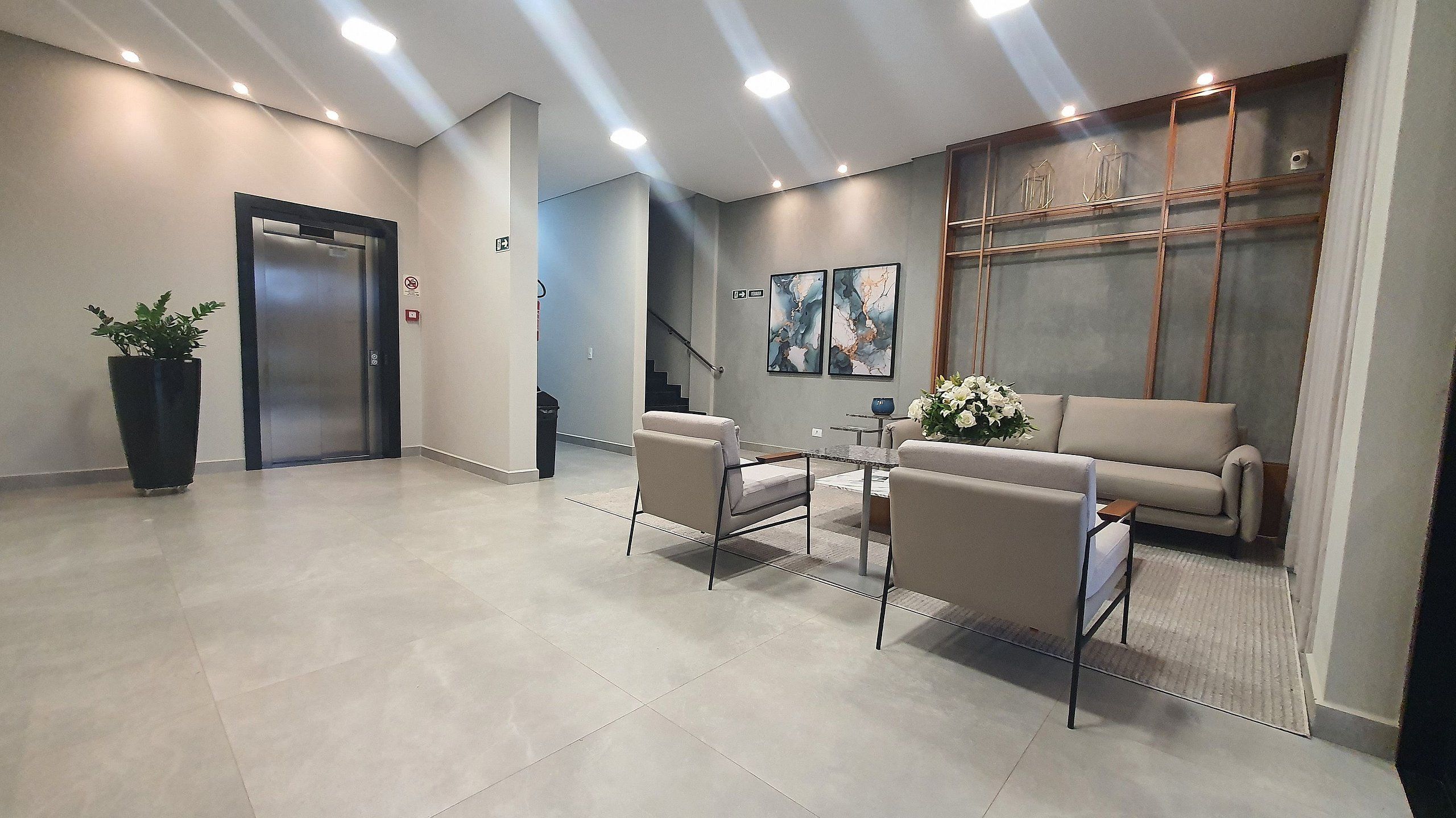 Um lobby moderno com balcão de recepção, área de estar e escadaria.