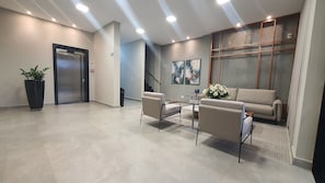 A modern lobby with a reception desk, seating area, and a staircase. - Residencial HS (Foz do Iguacu)