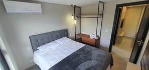 A hotel room with a bed, a bedside table, a mirror, and an air conditioning unit. - Residencial HS (Foz do Iguacu)