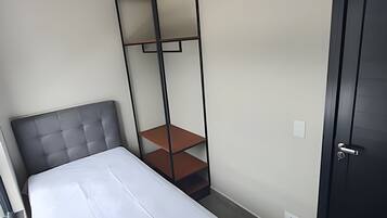 Un dormitorio con cama, armario empotrado y una puerta.
