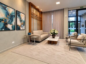 A modern waiting area with a sofa, chairs, a coffee table, and a vase of flowers. - Residencial HS (Foz do Iguacu)