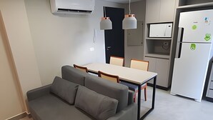 Una cucina moderna con zona pranzo, divano grigio e lampade a sospensione.