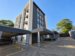 A modern building with a covered parking area and a car parked inside. - Residencial HS (Foz do Iguacu)