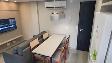 A modern kitchen with a dining table, chairs, a TV, and an air conditioning unit.