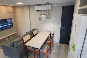 A modern kitchen with a dining table, chairs, a TV, and an air conditioning unit. - Residencial HS (Foz do Iguacu)