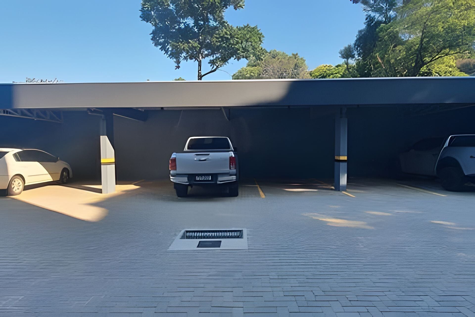 Un estacionamiento con dos coches aparcados, una camioneta blanca y un sedán blanco.