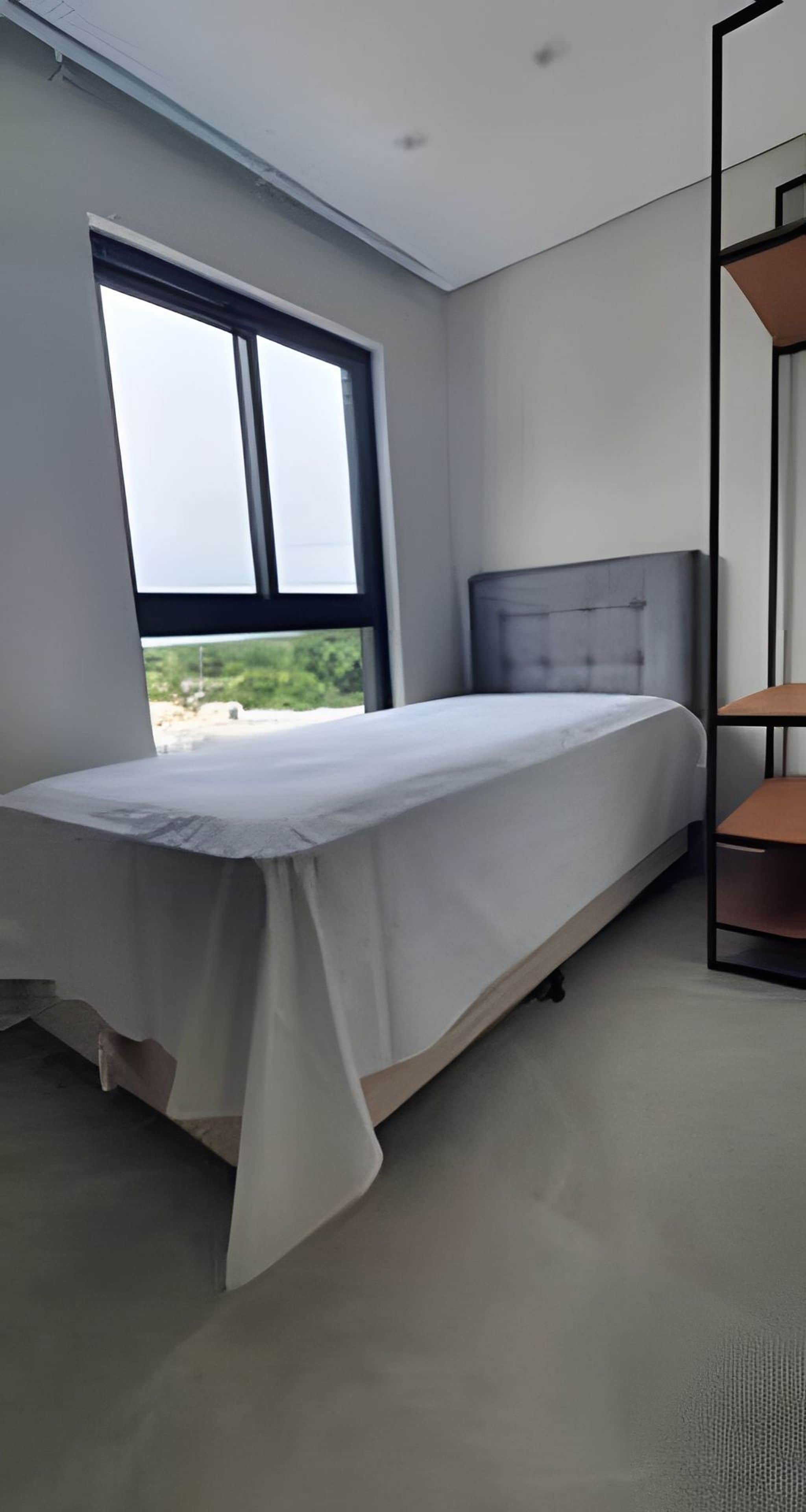 A bedroom with a bed, a window, and a built-in shelf.