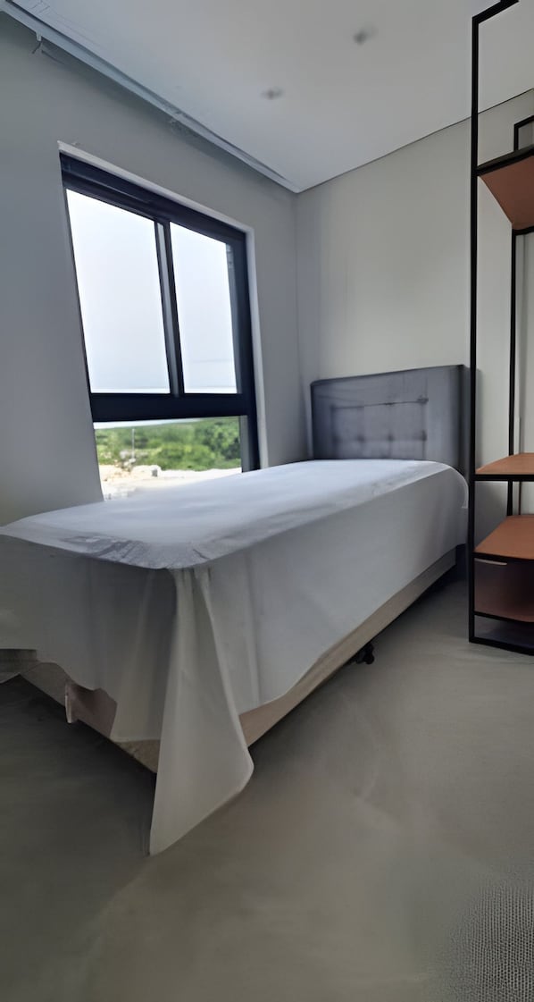 A bedroom with a bed, a window, and a built-in shelf. - Residencial HS (Foz do Iguacu)