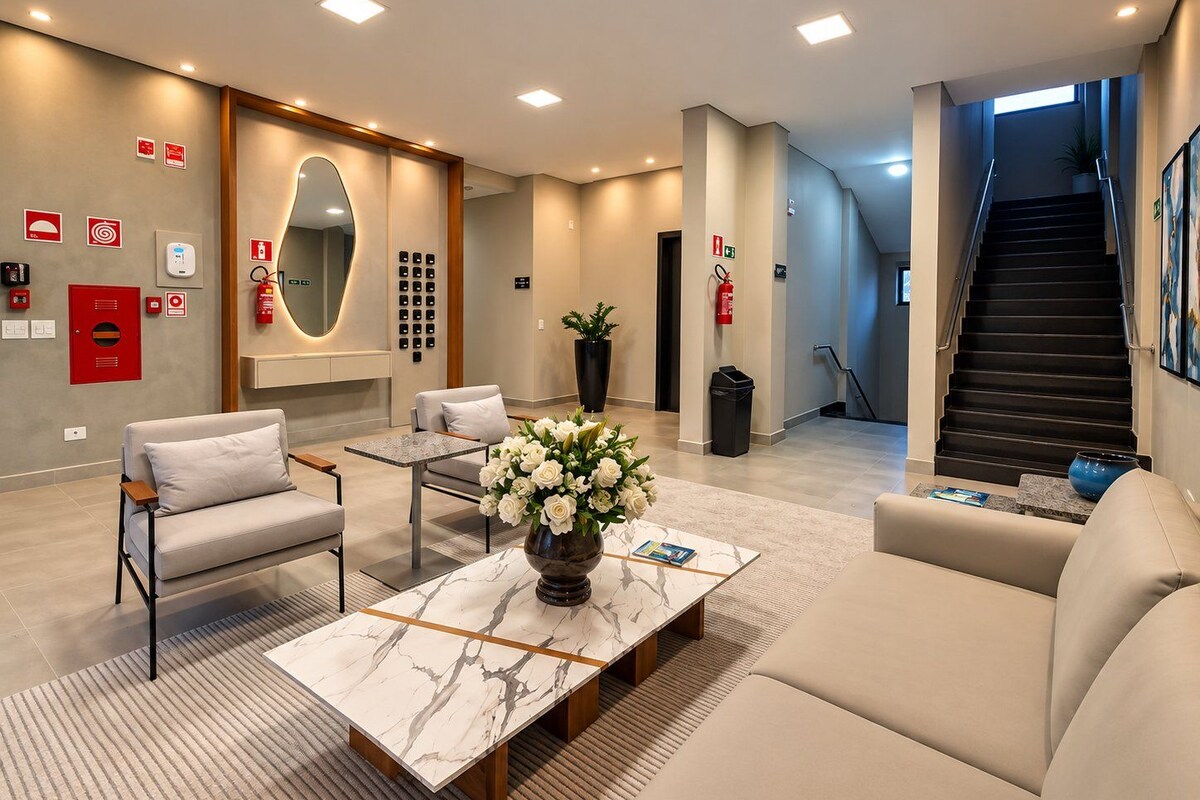 A modern hotel lobby with a marble coffee table, seating area, and a staircase.