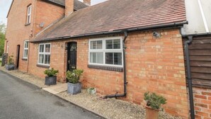 A two-story brick house with a tiled roof, a front door, and potted plants. - Charming 3 Bed Home with Garden & Parking near Worcester (Lower Broadheath)
