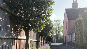 A gravel driveway leading to a residential area with a wooden fence and a brick house. - Charming 3 Bed Home with Garden & Parking near Worcester (Lower Broadheath)