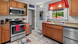 Una cocina moderna con armarios de madera, electrodomésticos de acero inoxidable y una cortina roja sobre la ventana.