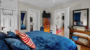 Un dormitorio con una cama grande, un aparador, un televisor y un espejo.