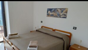 A bedroom with a bed, a nightstand, a painting on the wall, and a window. - In Posticastello ideal for a relaxing stay with family or company (Castelluccio Superiore)