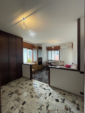 A spacious living area with a kitchen, a dining table, and a large wardrobe.