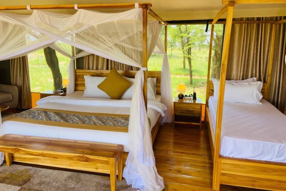 Una habitación con dos camas de madera, cada una con dosel, y un banco al frente.