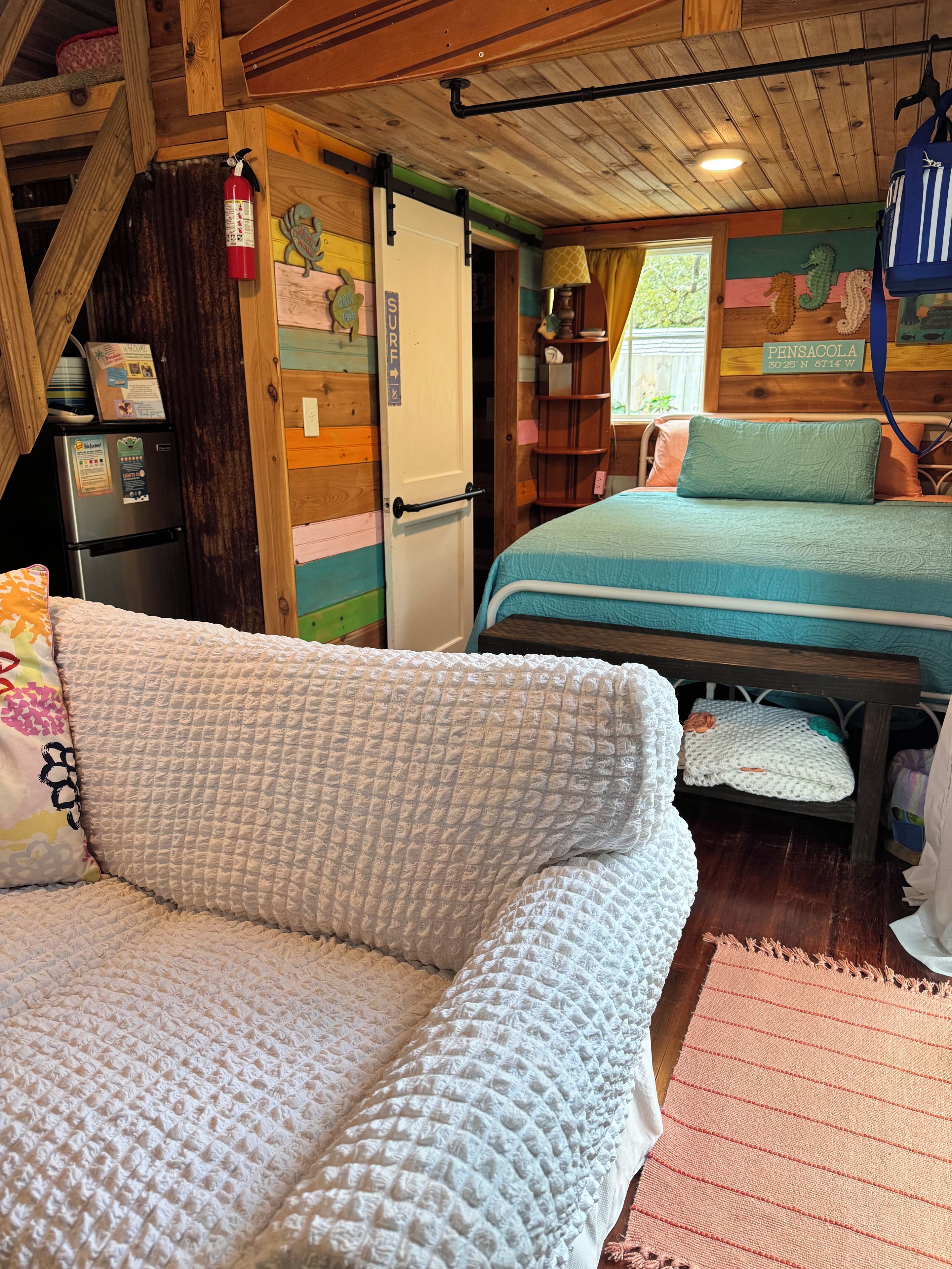A cozy room with a bed, a couch, and a refrigerator.