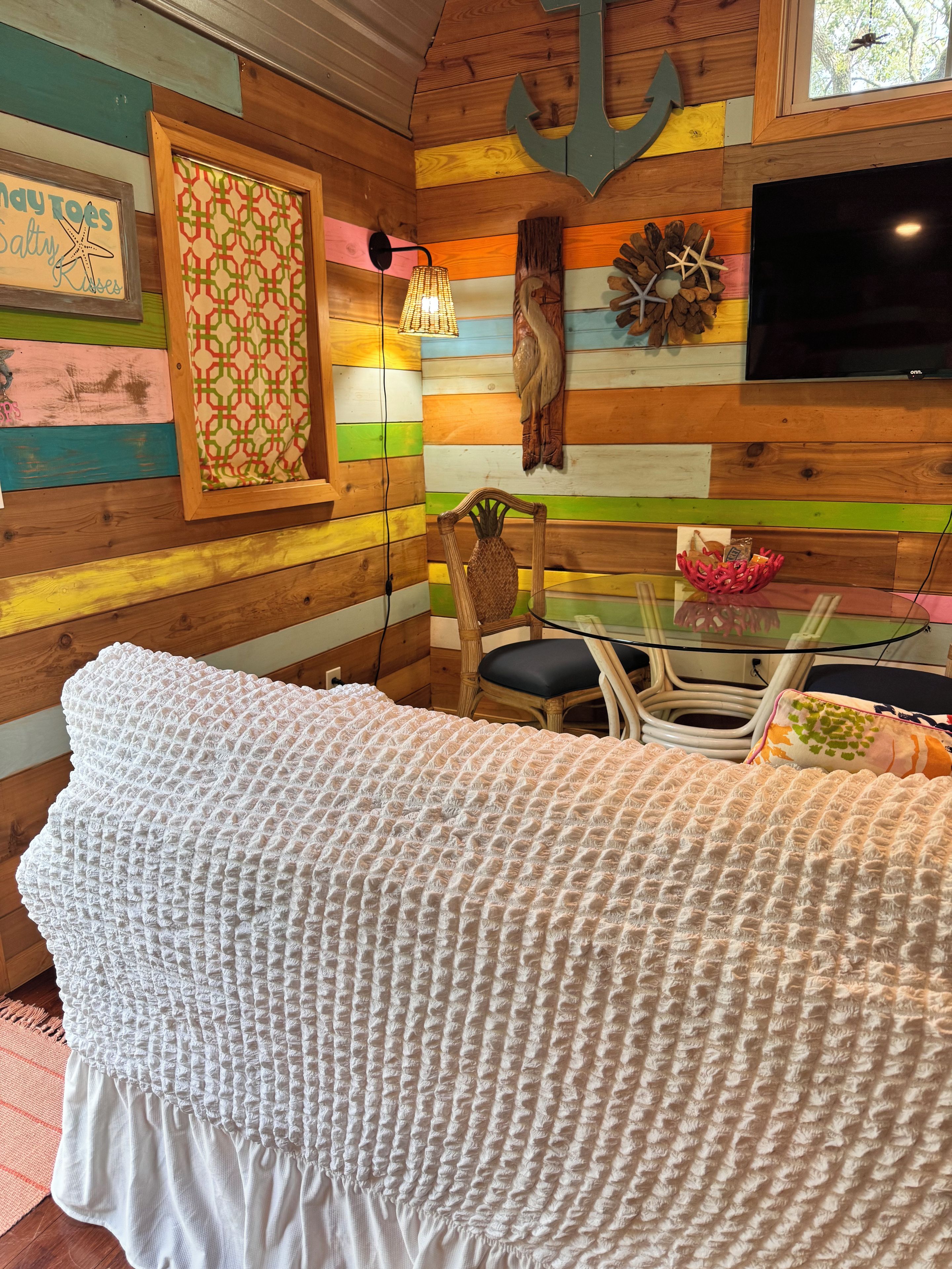 Une pièce comprenant un lit, un mur en bois orné de panneaux colorés, un téléviseur et un élément décoratif mural.