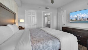 A hotel room with a bed, a ceiling fan, a TV, and a cityscape view. - Anderson Ocean Club #1611 (Myrtle Beach)