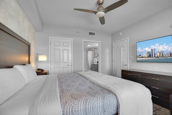 A hotel room with a bed, a ceiling fan, a TV, and a cityscape view. - Anderson Ocean Club #1611 (Myrtle Beach)