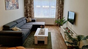 A modern living room with a grey sofa, a coffee table, and a TV mounted on the wall. - Vacation apartment König (Arendsee)