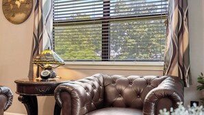 A leather armchair, a table with a lamp, and a window with blinds.