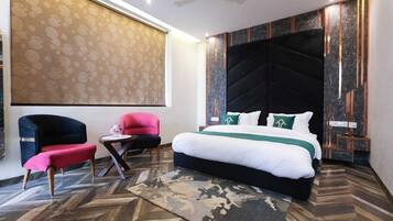 Una habitación de hotel moderna con una cama grande, un escritorio, dos sillas y un papel tapiz estampado.